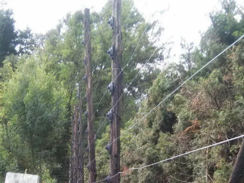 Cerca eléctrica de varios hilos instalada junto a cerramiento de madera